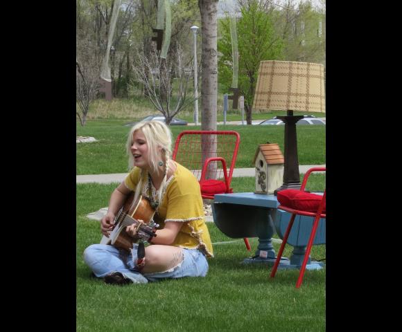 Woman sitting in grass playing guitar