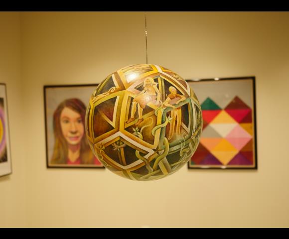 Painted sphere with people and snakes painted on