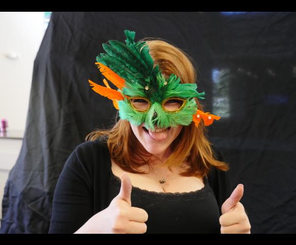 Lady holding a thumbs up with a green and orange mask on