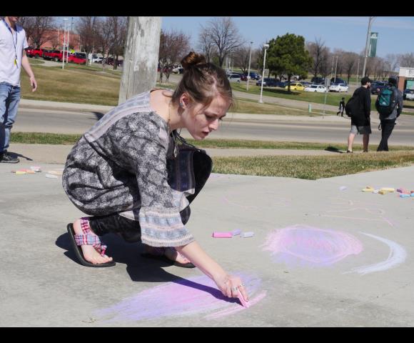 Child drawing on sidewalk with pink chalk