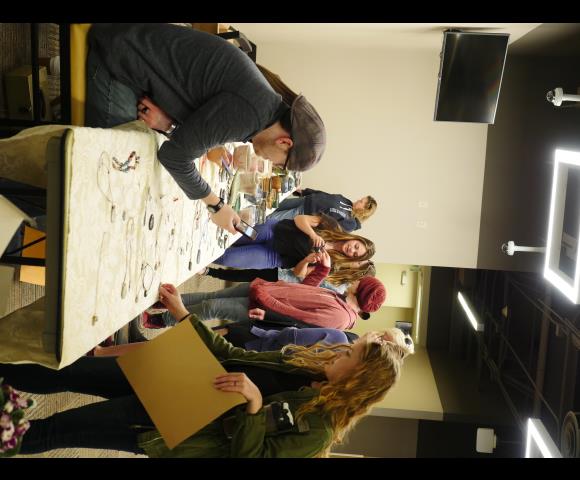 People looking at Raku-Fired Pottery and necklaces on table for show