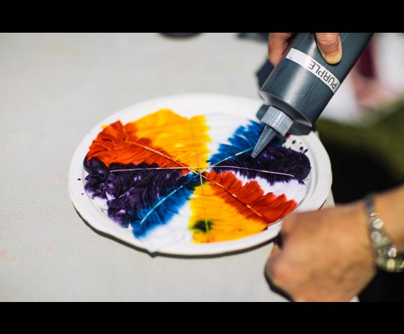 Pouring yellow, blue, red paint on plate