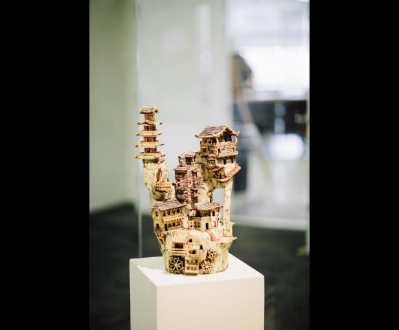 Intricate miniature village sculpture on a display pedestal.
