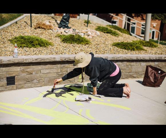 Person drawing on sidewalk with yellow chalk